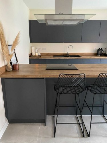 kitchen of MySymphonyStyle November winner. A dark grey anthracite kitchen with wood worktops and black barstools at a breakfast bar. A pampas grass vase features on the bar alongside a photo frame