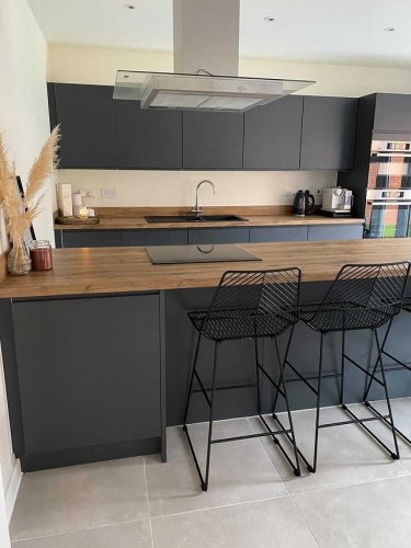 kitchen of MySymphonyStyle November winner. A dark grey anthracite kitchen with wood worktops and black barstools at a breakfast bar. A pampas grass vase features on the bar alongside a photo frame