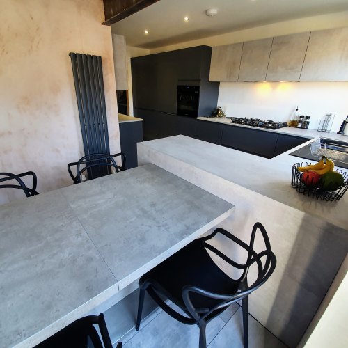 Kitchen with dining table and chairs. U shaped space with a handleless grey kitchen door and a faux concrete kitchen door with concrete effect worktop
