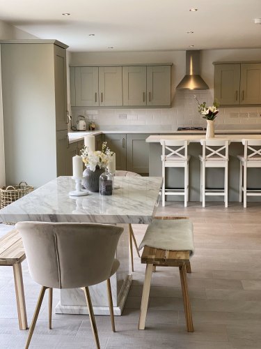Cranbrook sage green kitchen with white worktop and brass kitchen handles with white bar stools and a marble dining table with benches 