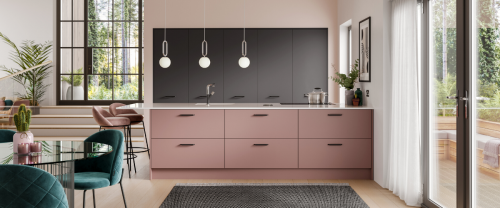 Pink kitchens units on a kitchen island, with tall anthracite dark units to the rear of the space. Windows and indoor plants fill the space, along with a dining chair and bar stools